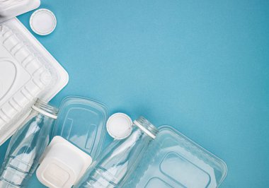 Mavi arka planda şişeleri olan tek kullanımlık plastik sofra takımı. Çevre kirliliğini ve ekolojiyi önlemek için insanları plastik maddeler kullanmamaya teşvik etme kavramı. Plastiğin reddedilmesi.