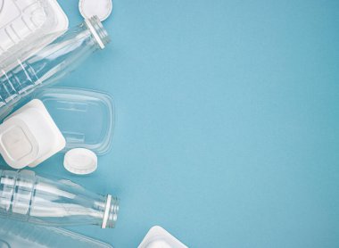 Mavi arka planda şişeleri olan tek kullanımlık plastik sofra takımı. Çevre kirliliğini ve ekolojiyi önlemek için insanları plastik maddeler kullanmamaya teşvik etme kavramı. Plastiğin reddedilmesi.