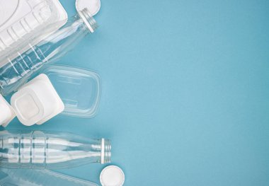 Mavi arka planda şişeleri olan tek kullanımlık plastik sofra takımı. Çevre kirliliğini ve ekolojiyi önlemek için insanları plastik maddeler kullanmamaya teşvik etme kavramı. Plastiğin reddedilmesi.