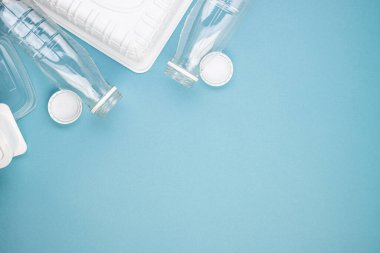 Boş plastik şişeler, beyaz kapaklar, paketler ve tabaklar yığınla. Çevre kirliliğini ve ekolojiyi önlemek için insanları plastik maddeler kullanmamaya teşvik etme kavramı