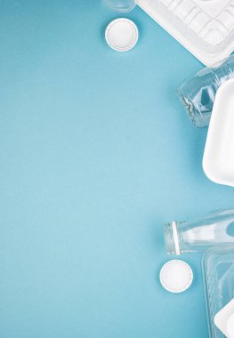 Mavi arka planda şişeleri olan tek kullanımlık plastik sofra takımı. Çevre kirliliğini ve ekolojiyi önlemek için insanları plastik maddeler kullanmamaya teşvik etme kavramı. Plastiğin reddedilmesi.