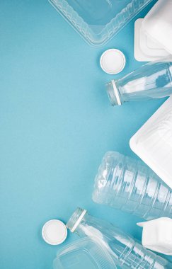 Boş plastik şişeler, beyaz kapaklar, paketler ve tabaklar yığınla. Çevre kirliliğini ve ekolojiyi önlemek için insanları plastik maddeler kullanmamaya teşvik etme kavramı