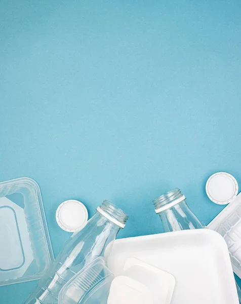 Disposable plastic tableware with bottles on a blue background. The concept of encouraging people not to use plastic items to prevent environmental pollution, ecology. The rejection of the plastic