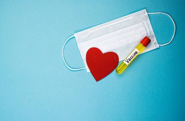Covid-19 aşısını içeren bir ampul, virüsün tüm dünyaya yayılmasını engellemek için icat edildi. Mavi arka planda kırmızı kalpli bir maske