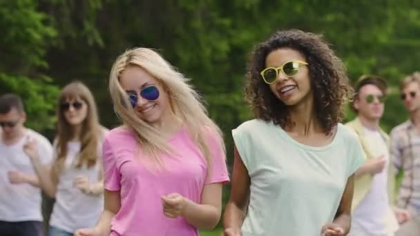 Pareja de chicas calientes bailando con amigos en el festival al aire libre, disfrutando del verano — Vídeo de stock