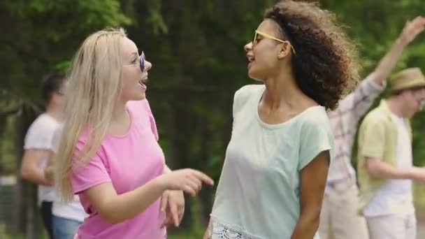 Две счастливые танцовщицы наслаждаются вечеринкой на открытом воздухе, друзья тусуются в парке — стоковое видео