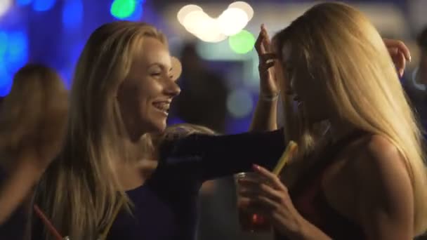 Bisexuell heiße Damen, die sich auf der Tanzfläche bei einer Nachtclubparty umarmen und lachen — Stockvideo