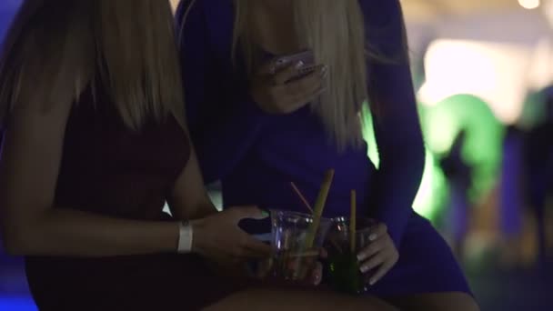 Две красивые дамы печатают сообщения на смартфонах на скучной коктейльной вечеринке — стоковое видео
