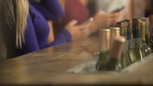 Jovens mulheres esperando por bebidas no balcão do bar, usando gadgets, dançando à música — Vídeo de Stock