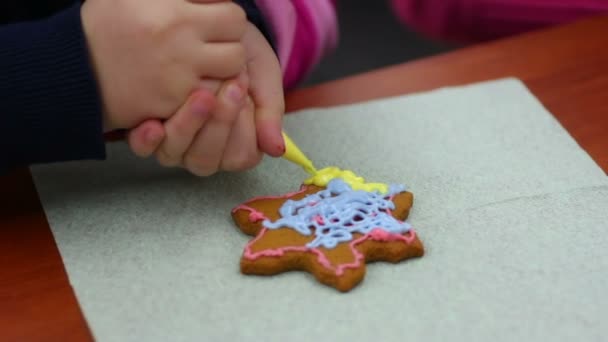 Внимательный ребенок украшает пряники в форме звезды с кондитерской глазурью — стоковое видео