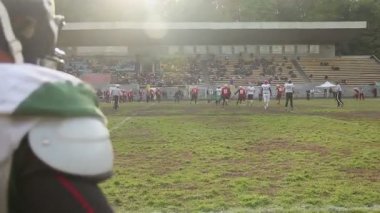 Amatör Amerikan futbolu maçında saldırıyı izleyen yedek oyuncular ve taraftarlar