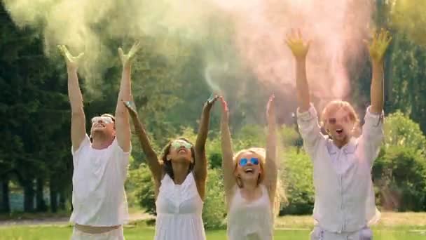 Gruppo multiculturale di amici che lanciano polvere colorata sopra le teste al festival — Video Stock