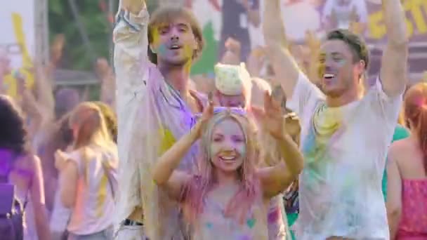 Usmívající se mladí pokryté barevný prášek tančí na Holi festivalový koncert — Stock video