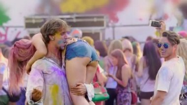 Holi festivalinde, çılgın eğlence dans genç sarhoş adam holding seksi kadın omuzlarında,