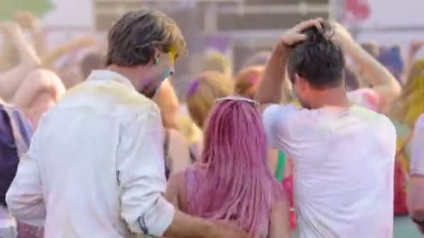 Jovens amigos positivos dançando, acenando com as mãos no festival Holi perto do palco do concerto — Vídeo de Stock