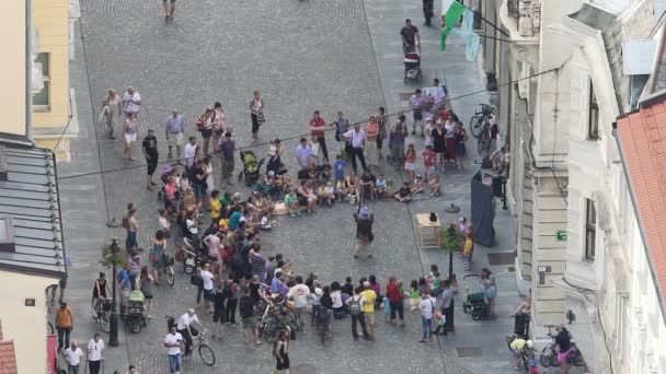 LJUBLJANA, SLOVENIEN - CIRCA JULI 2016: Folk på gaden. Tryllekunstner omgivet af publikum udfører på gaden, folk nyder underholdning – Stock-video