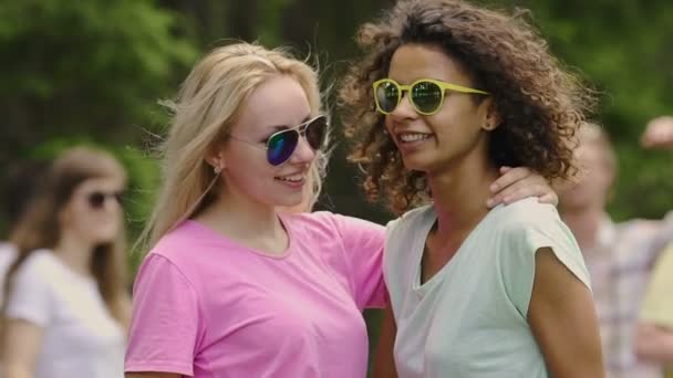 Mujeres guapas jóvenes en gafas de sol amarillas bailando con amigos, relajación en el parque — Vídeo de stock