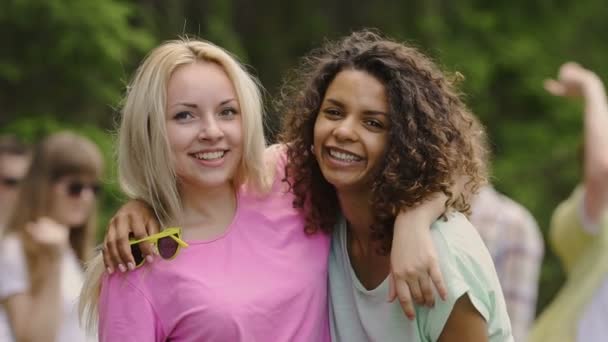 Giovani ragazze sane che si abbracciano, sorridono alla macchina fotografica, ballano con gli amici all'aperto — Video Stock