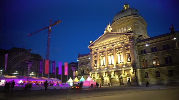 Ludzie chodzą w pobliżu oświetlony federalny pałac z lodowiskiem w Bern, Szwajcaria — Wideo stockowe
