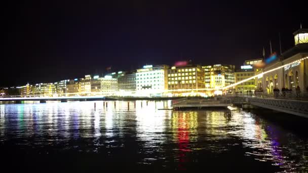 Beautiful Geneva lake at night, reflections in water, people walk on embalmment — Stock Video