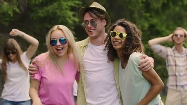 Возбужденные молодые люди в солнечных очках смеются и обнимаются, наслаждаются вечеринкой вместе — стоковое видео