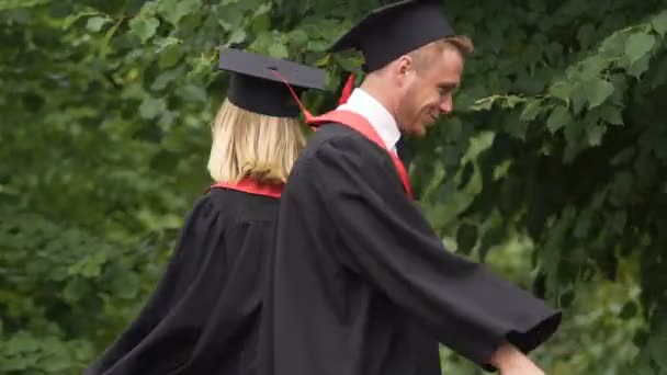 Šťastný pár postgraduální studenti tance a blbnout, drží diplomy — Stock video