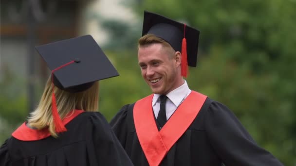 Felizes graduados masculinos e femininos comemorando a formatura, abraçando, futuro feliz — Vídeo de Stock