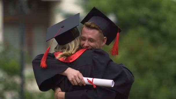 Feliz hombre felicitando y abrazando a la mujer joven en el día de la graduación, logro — Vídeo de stock