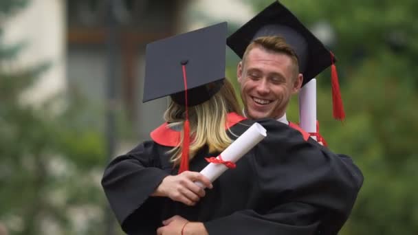 Legrační absolvent objímala jeho přítelkyni a směje se, úspěch, šťastnou budoucnost