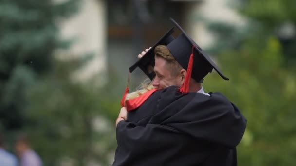 Dos amigos abrazándose en la ceremonia de graduación, jóvenes celebrando el logro — Vídeo de stock
