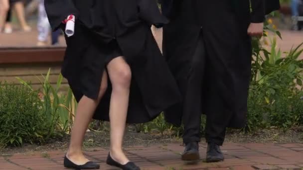 Feliz macho y hembra estudiantes bailando y divertirse después de la ceremonia de graduación — Vídeos de Stock