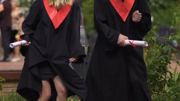 Estudiantes divertidos vestidos académicos bailando y disfrutando de la vida, celebrando el logro — Vídeo de stock