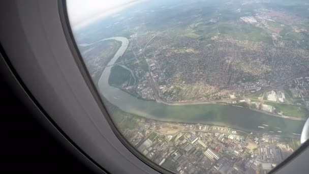 Großstadt am Ufer des breiten Flusses, schöne Aussicht aus der Luft durch Flugzeugfenster — Stockvideo