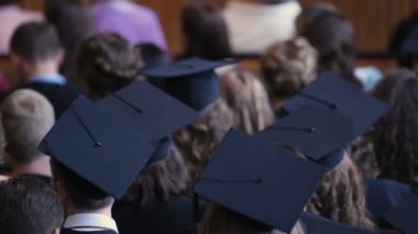 Birçok genç erkek ve kadın Üniversitesi Meclis Binası'nda oturan akademik kapaklar