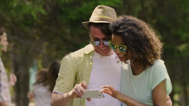 Pareja multiracial tomando selfie y viendo fotos en smartphone, felicidad — Vídeo de stock