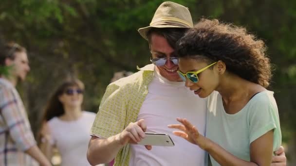 Jóvenes multiétnicos viendo fotos divertidas en el teléfono inteligente en la fiesta, fin de semana — Vídeos de Stock
