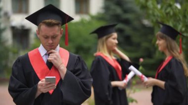 Yakışıklı mezunu iş teklifleri denetimi iletileri smartphone, yazarak manto içinde