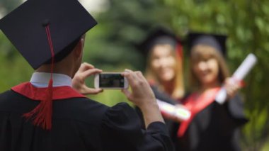 İki diploma tutarak ve akıllı telefon fotoğraf makinesi, mezuniyet poz kızlar mezun