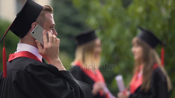 Beszélő smartphone és mosolyogva, diplomaosztó nap boldog férfi diplomás — Stock videók