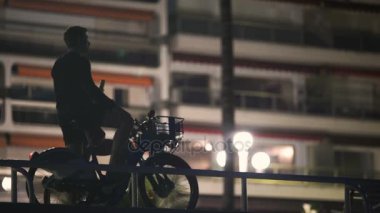 Mobil app kullanarak sağlıklı genç adam zevk Bisiklete binme seyahatinden gece şehir,