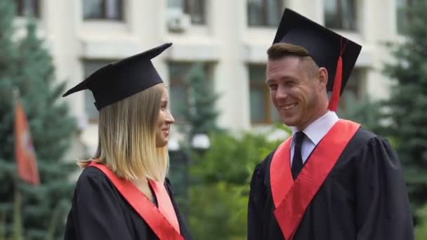 Kadın ve erkek öğrencilere konuşan mutlu arkadaşlar Üniversitesi'nden mezun — Stok video