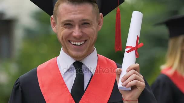 Estudiante graduado feliz y orgulloso con certificado de educación superior en la mano — Vídeo de stock