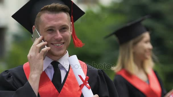 Feliz estudiante masculino hablando por teléfono, recibiendo felicitaciones por la graduación — Vídeo de stock