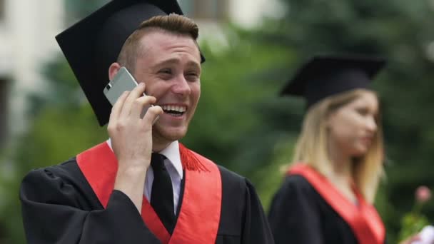 Hombre graduándose estudiante disfrutando de conversación telefónica y riendo alegremente — Vídeo de stock