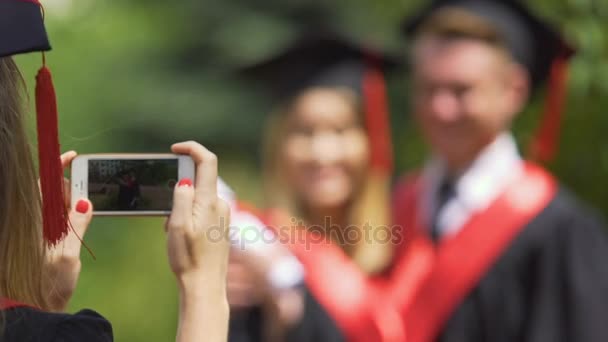 Pareja joven de graduados universitarios abrazando y posando para la foto, pulgares arriba — Vídeo de stock