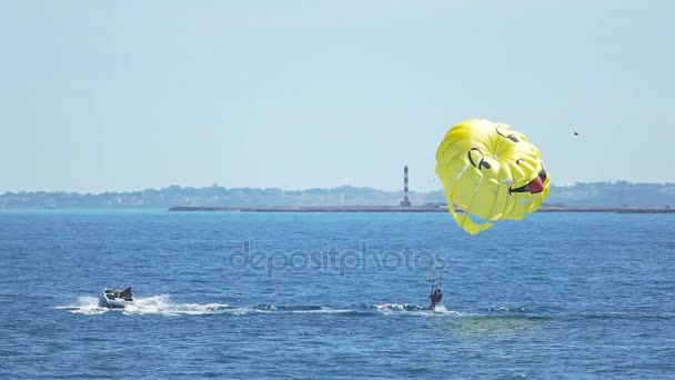 Счастливые люди на парашюте над синим морем, парашютные виды спорта, летние развлечения — стоковое видео