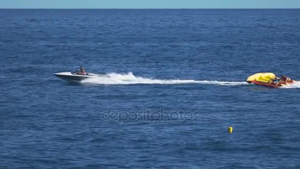 People riding inflatable banana mattress on summer vacation, cool activity — Stock Video