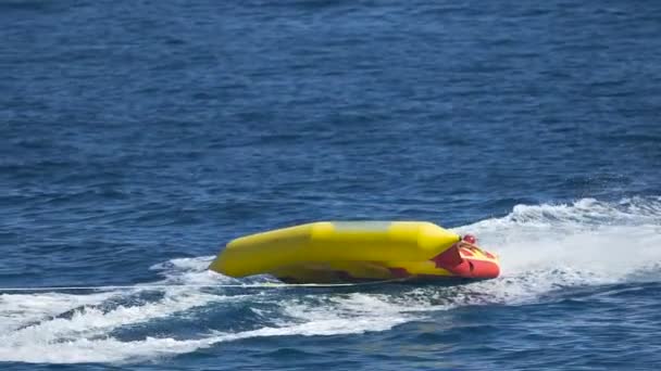 Children riding banana boat, speed floating, summer water attraction in slow-mo — Stock Video