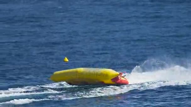 Young people riding large size inflatable boat and jumping on waves, vacation — Stock Video