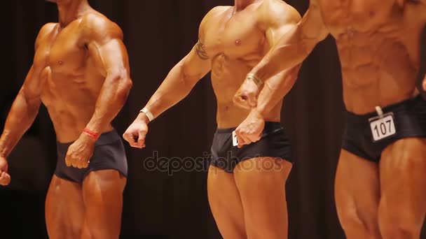 Мужчины культуристы хвастаются мускулистыми телами на сцене, результатом тяжелых тренировок — стоковое видео